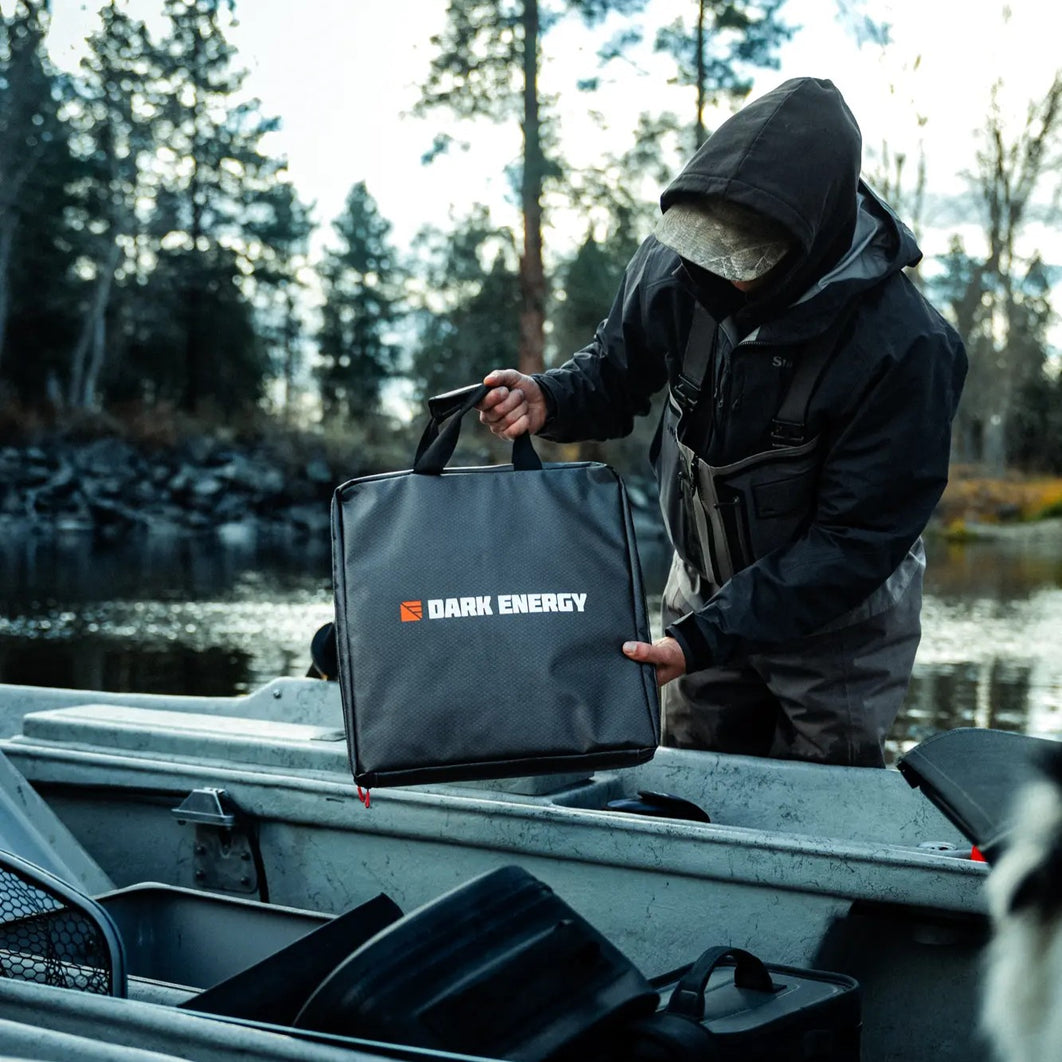 A person lifting the Spectre accessories case from a truck bed by a river.