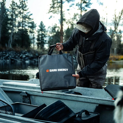 A person lifting the Spectre accessories case from a truck bed by a river.