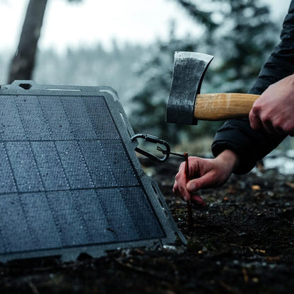 A person staking the Spectre solar panel to the ground with a hatchet.