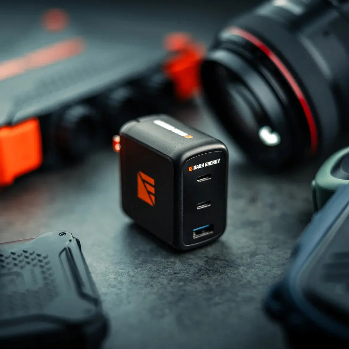 The Dark Energy 65W charger beside camera equipment.