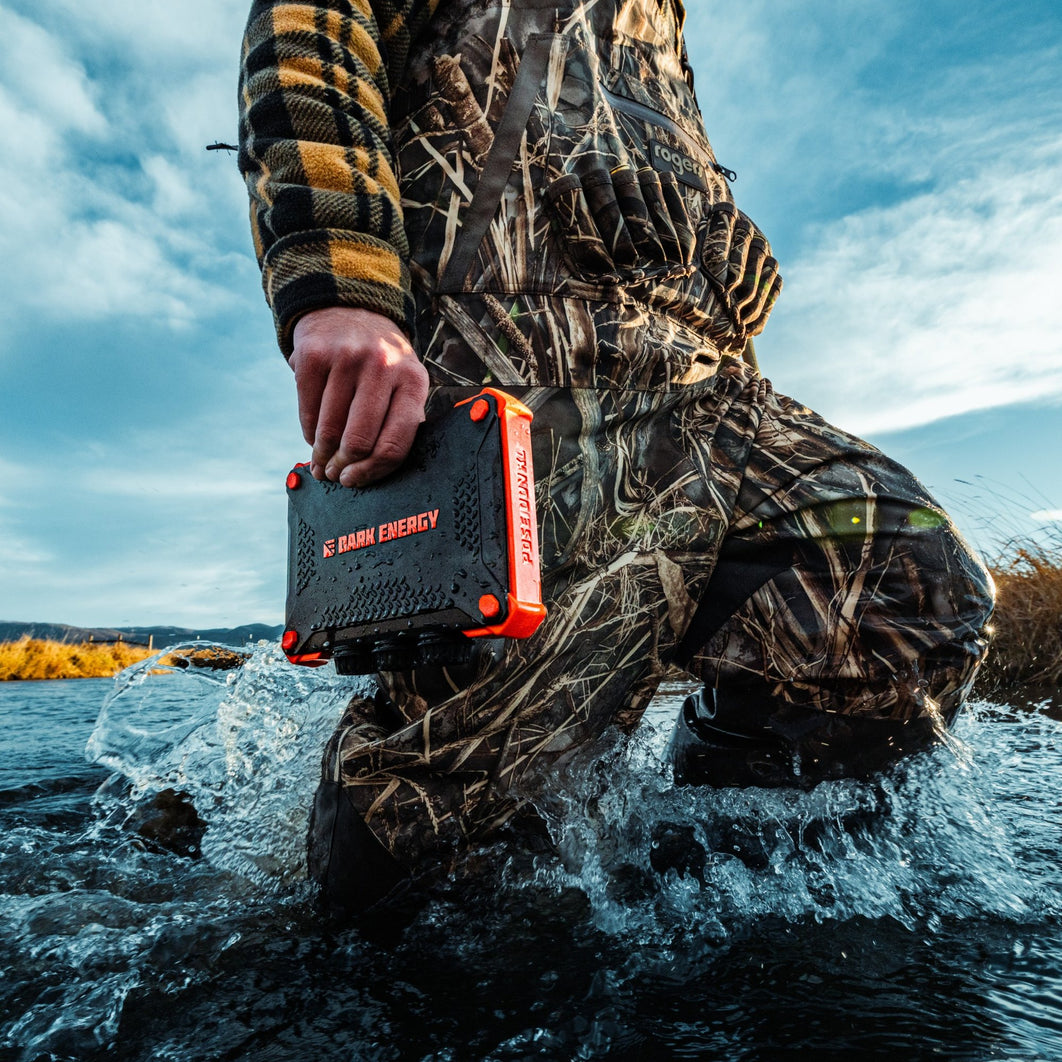 A person carrying the Poseidon XL power bank while wading through water.
